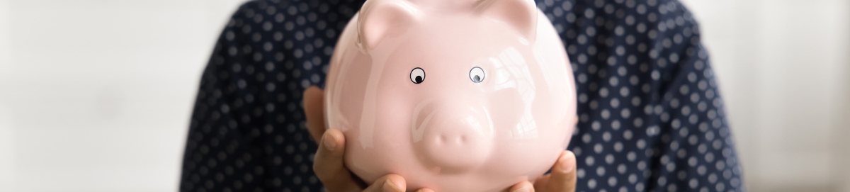 Smiling female student holding a piggy bank.