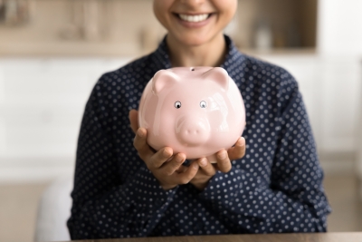 Smiling female student holding a piggy bank.
