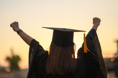 Photo of female college graduate raising her arms in success