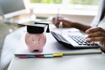 Student using calculator next to piggy bank