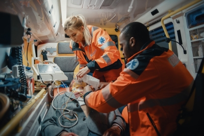 Female and male paramedic inside ambulance attending a person.